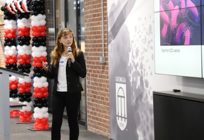 photo of woman presenting, with microphone and screen