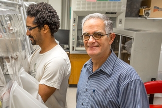 two men in a lab, one looking at camera