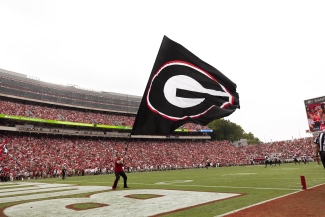 photo of man with large flag in the end zone at the stadium during a football game