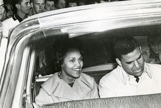 b/w photo of two people in a car, from outside