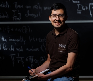 photo of man, chalkboard with letters and numerals in background