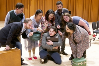 photo of eight people on a stage with suitcases