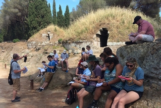 students with professor at ancient tomb opening