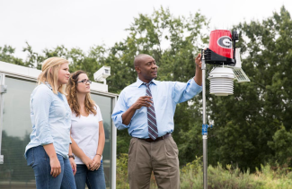 photo of man and two women with weather station