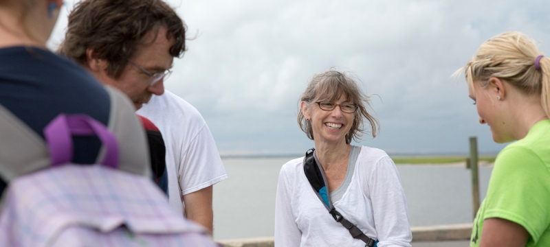 photo of people on a dock near water, woman at center 