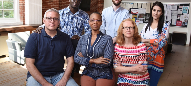 photo of six people, inside with brick wall