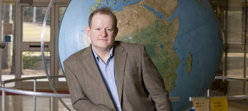 photo of man in front of large globe