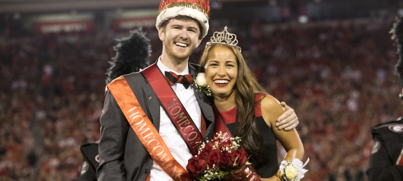 photo of couple with crowns at football stadium, night, blurred crowd background