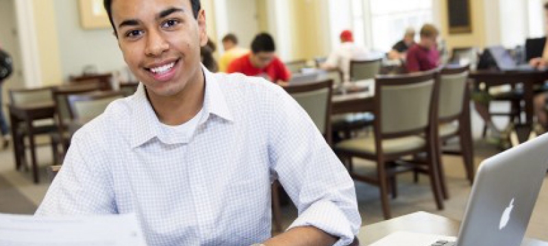 student in classroom with laptop and paper