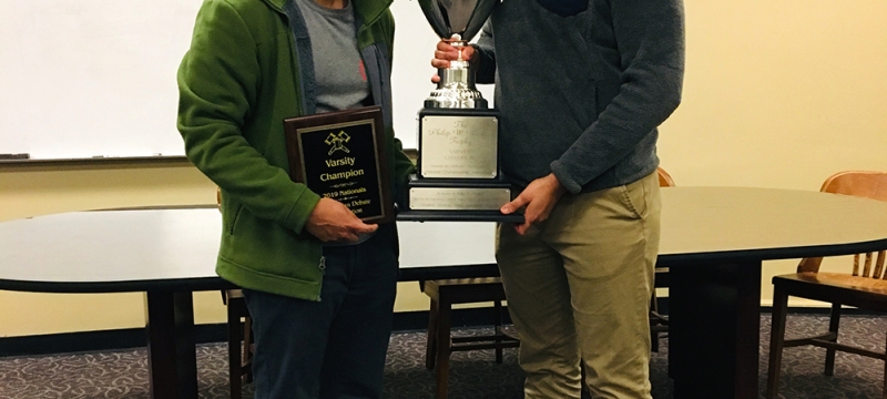 photo of two men with trophy and plaque