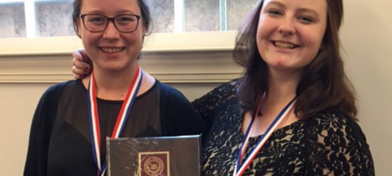 two women with plaque and medals