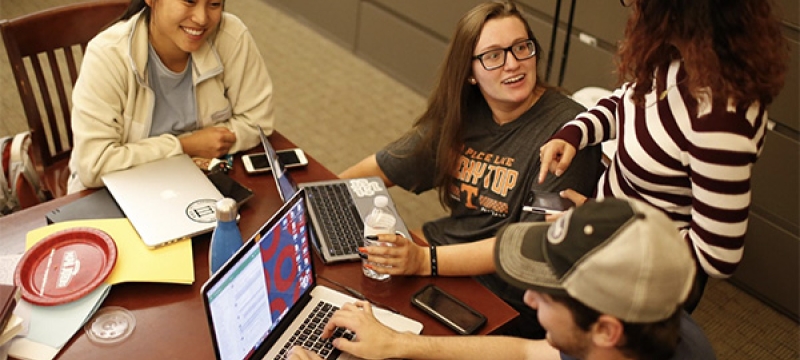 photo of four people at a table, with laptop