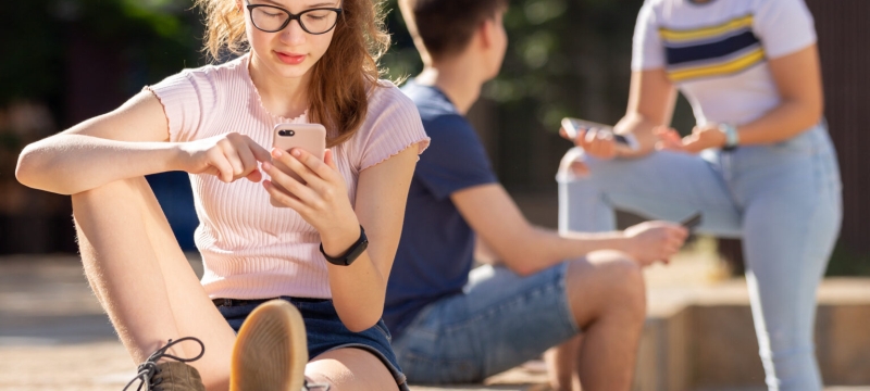 young people outside on their phones