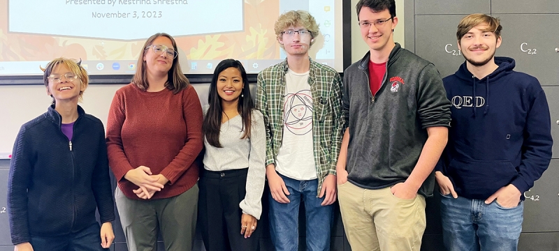 group photo of six people, with projection screen in background