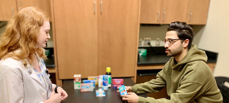 photo of two people at table with medicinal products