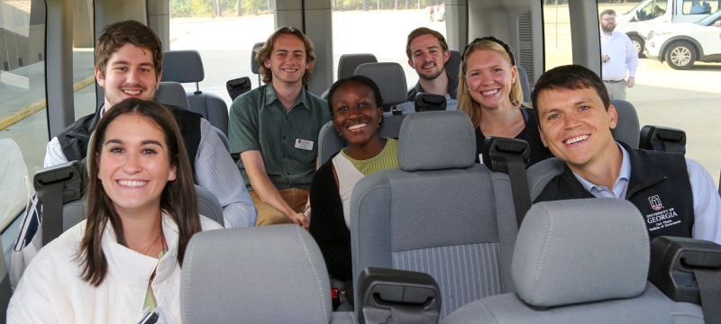 photo off seven smiling students inside a van
