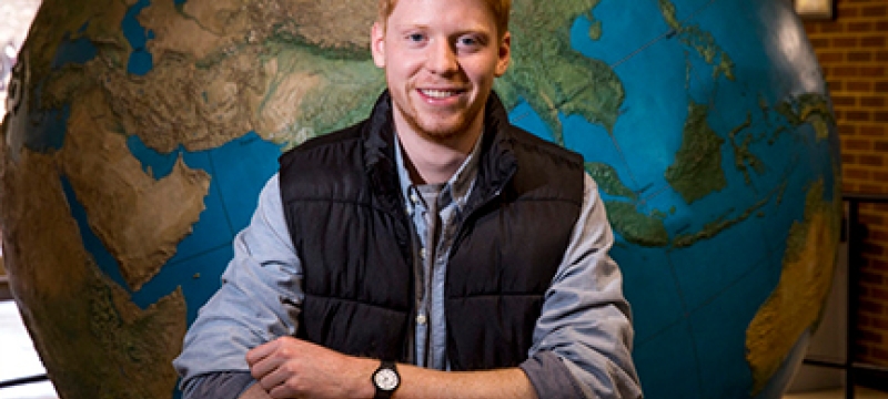 photo of man in front of globe