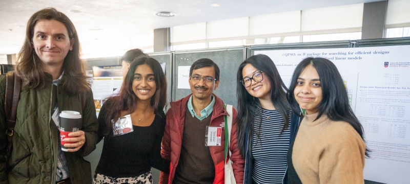 photo of five people, poster in background
