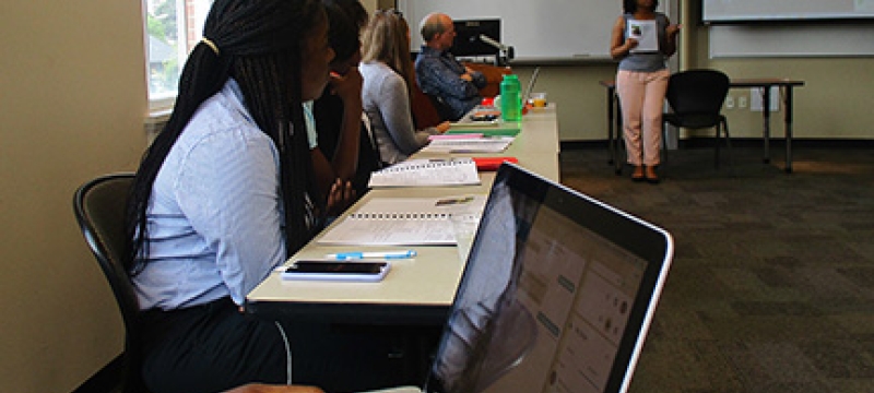 students in a classroom, macbook foreground