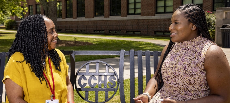 photo of two women sitting on bench outdoors, day