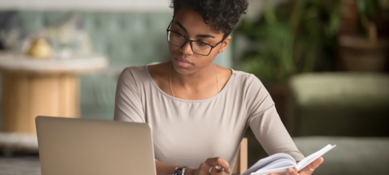 photo of woman with book and laptop