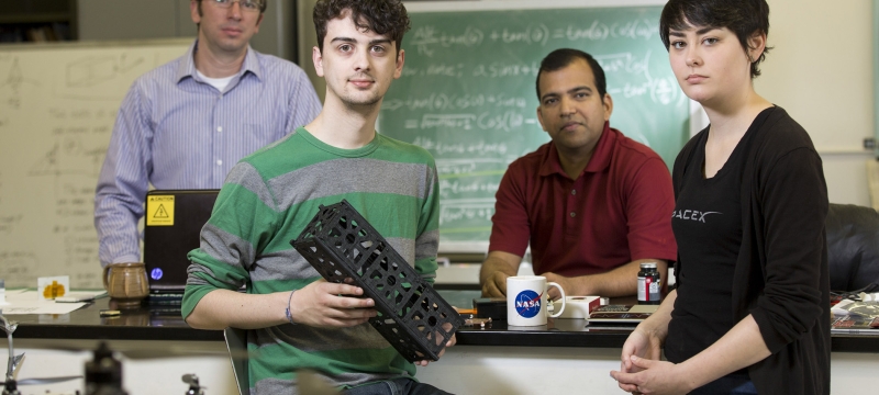 photo of four people in lab, man in foreground with small rectangular box