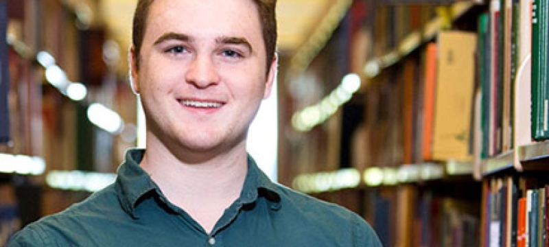 man with library shelves and books