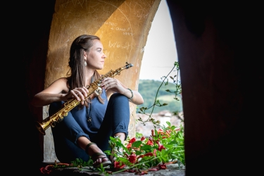 photo of woman sitting in arch opening with musical instrument