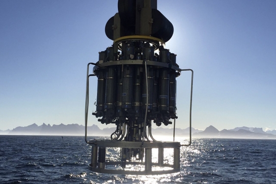 photo of scientific device suspended about sea, mountains and sky in background