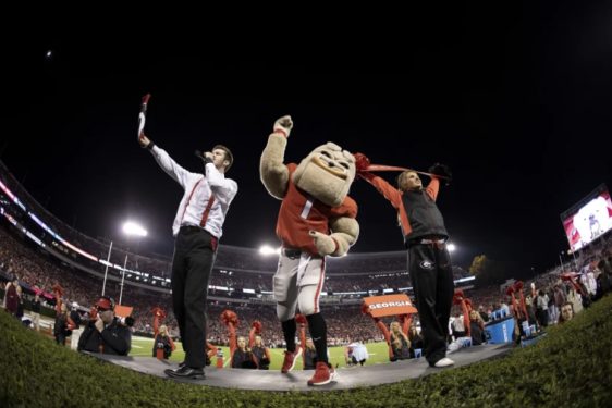 photo of man in stadium with mascot, night