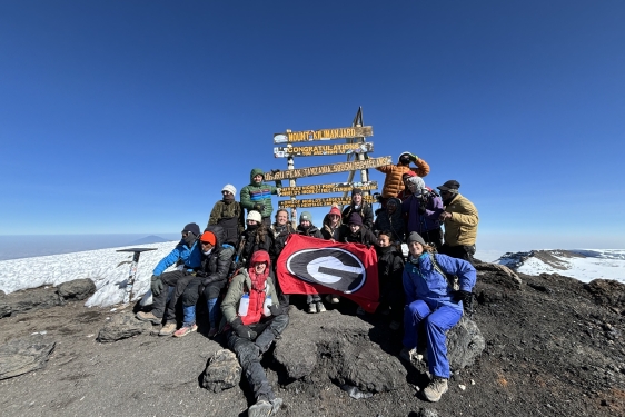 group photo of people on mountain top, with signs, snow