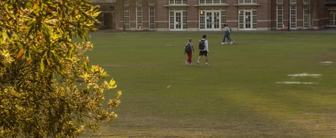 photo of students on quad near sunset, building in background