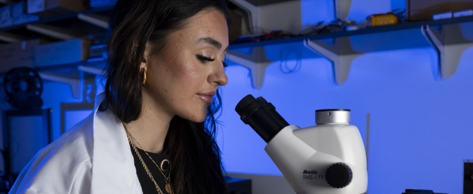 photo ofo woman with microscope, lab coat, gloves