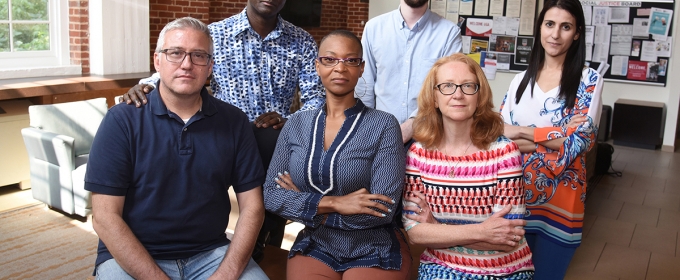 photo of six people, inside with brick wall