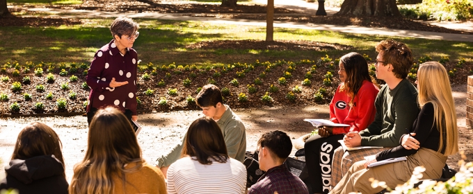 photo of professor and group of students outdoors, day