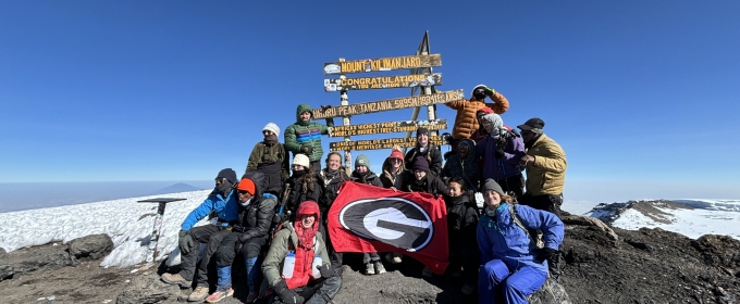 group photo of people on mountain top, with signs, snow