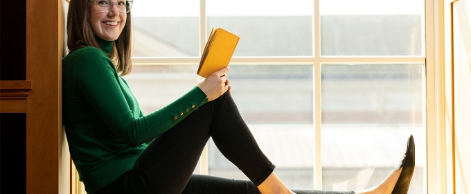 photo of woman with book in window sill